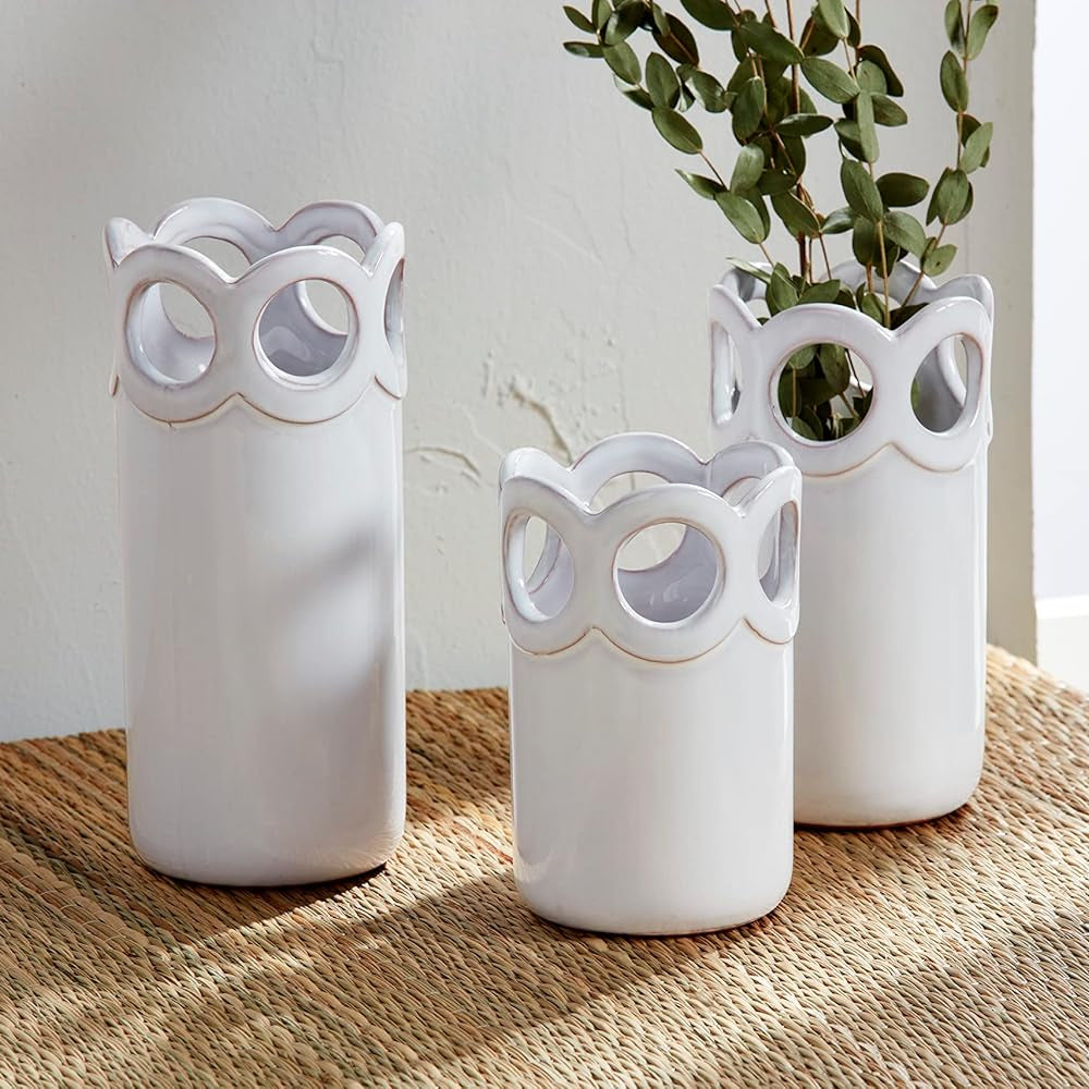 all three sizes of the scalloped bud vases displayed on a tan runner with one having dried greenery