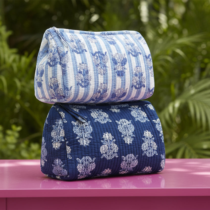 blue floral zipper bags stacked on a pink table with greenery background