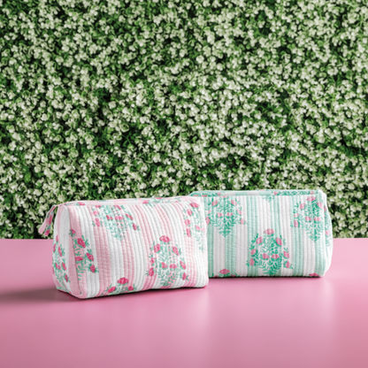 Floral-patterned cylindrical pouches in pink and green on a pink surface with a green and white floral background