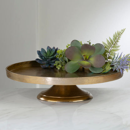 large round gold pedestal with greenery on it