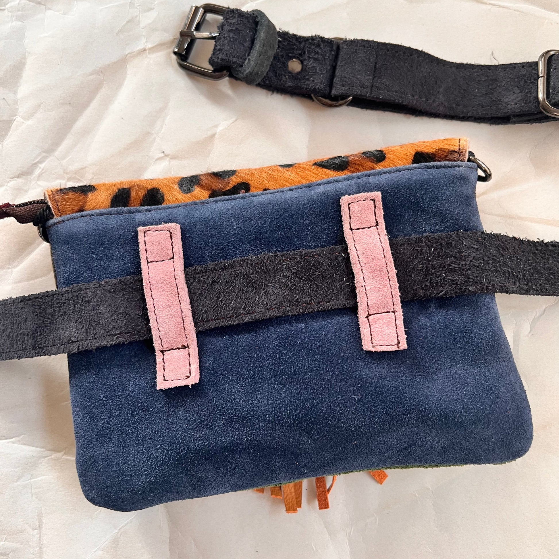 solid blue back of bag with pink loops holding grey belt.