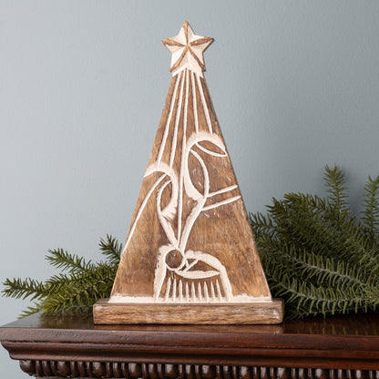 carved scene of holy family with star above them set on a mantle with greenery.