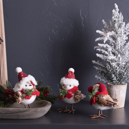 three winter birds displayed on a dark table next to a small flocked tree and oval tray