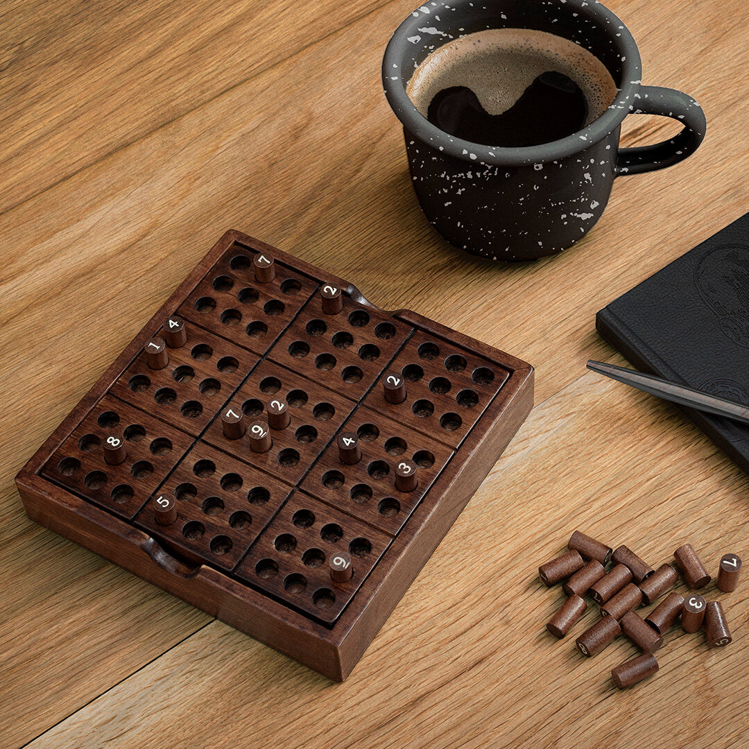 Wooden Sudoku game on a desk with a laptop and cup of coffee.