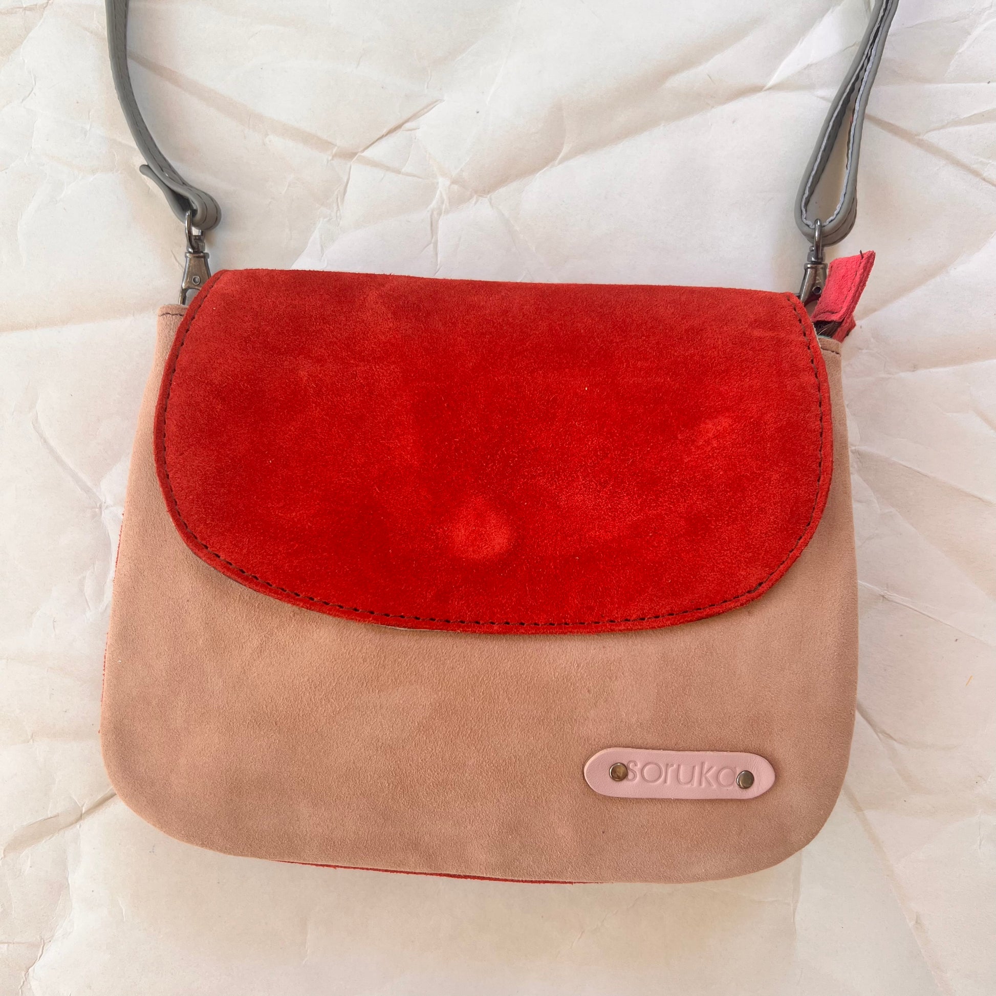 leo purse with blush body and red flap.