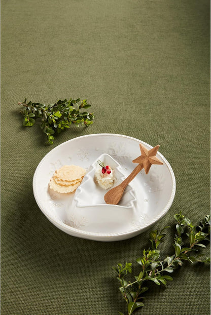 snowflake chip and dip dish set on a table with crackers and dip in it and sprigs of greenery around it.