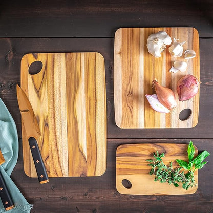 3 sizes of boards arranged on a wooden slat surface with a knife, herbs and onions.