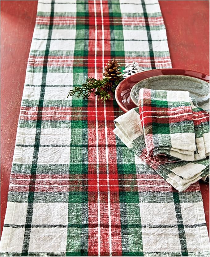 festive plaid runner on a red table with plates, napkins, and a sprig of greenery set on the side.