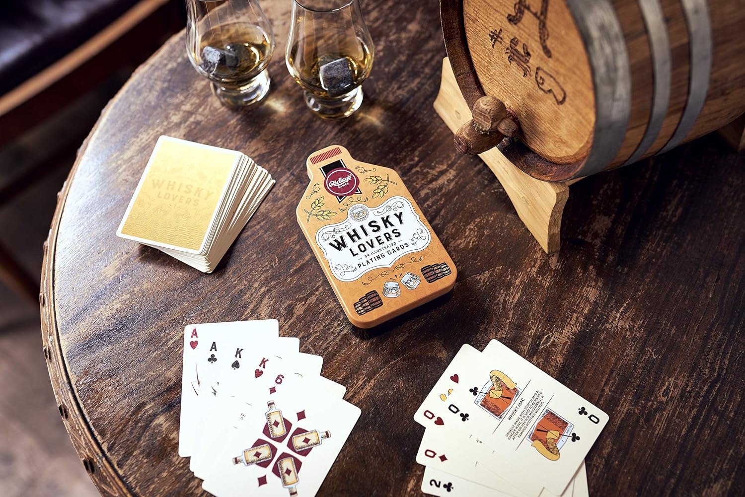 whiskey lovers cards and tin set on a wooden table with beverages and a whiskey barrel.