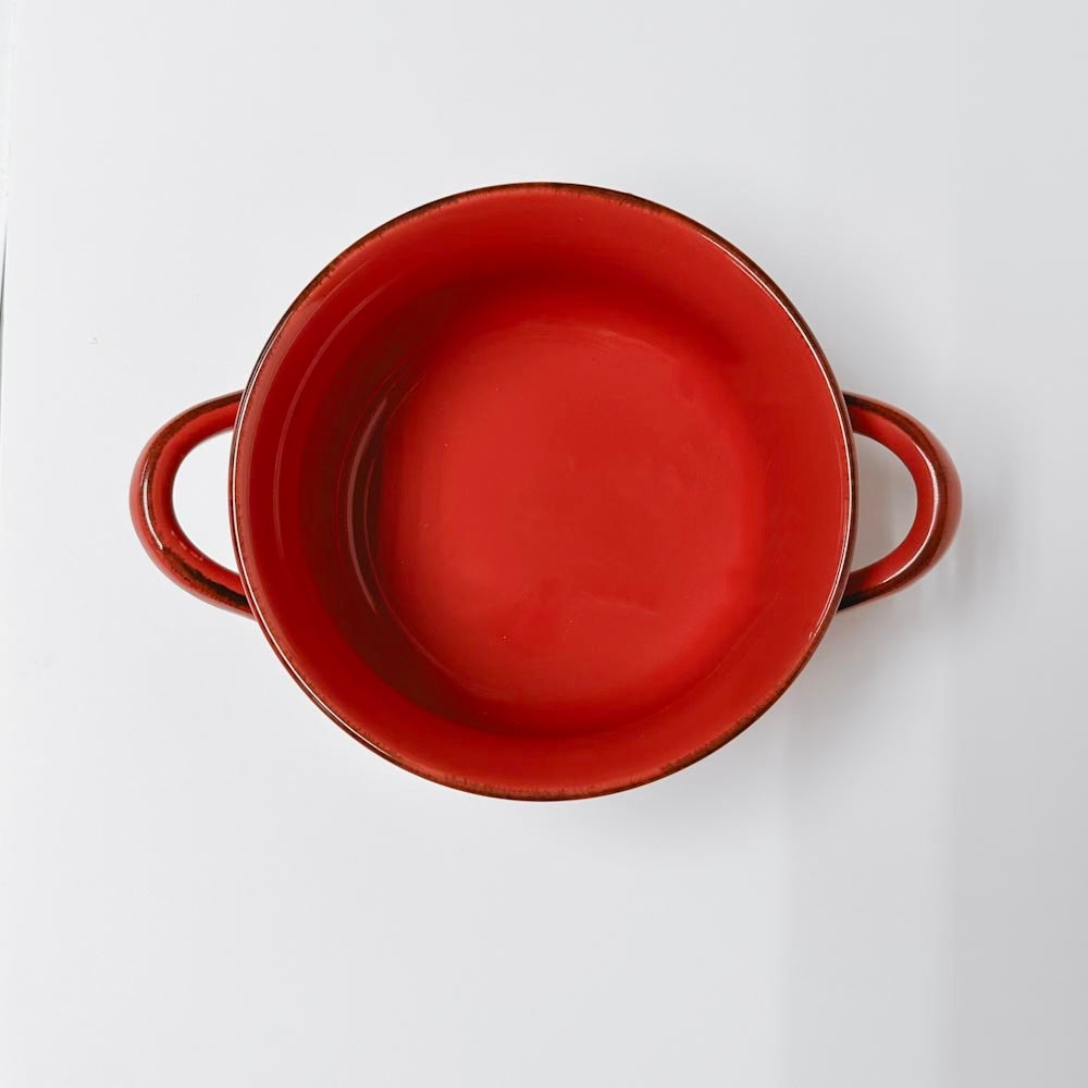 top view of red handled soup bowl on a white background.