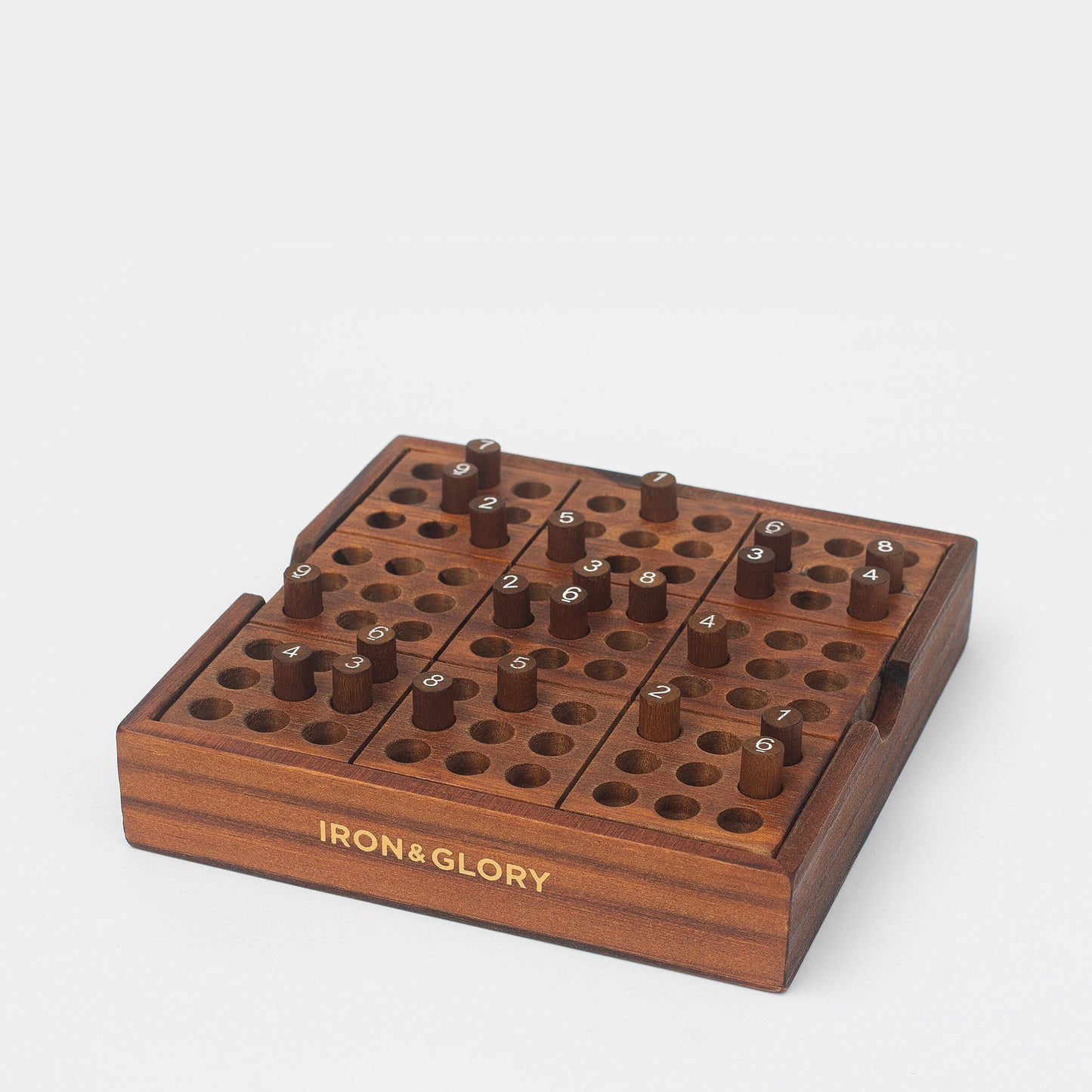 Side view of wooden Sudoku game with some numbered pegs in slots.