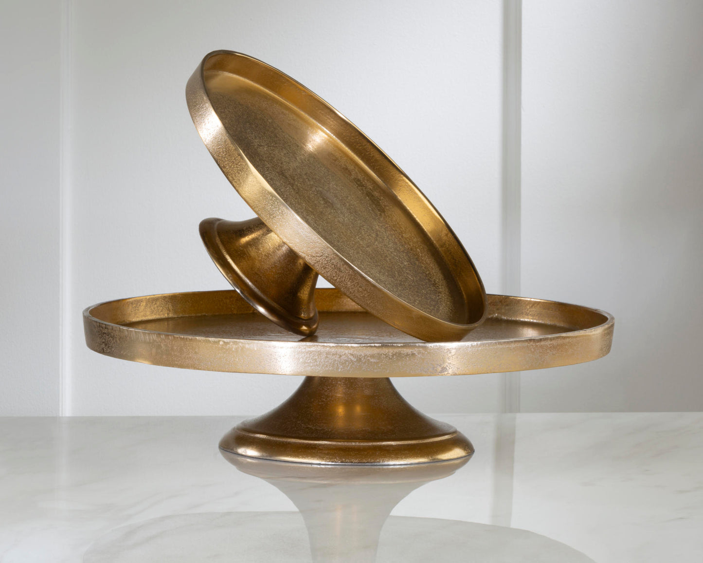 2 gold pedestals stacked with the small one set at an angle