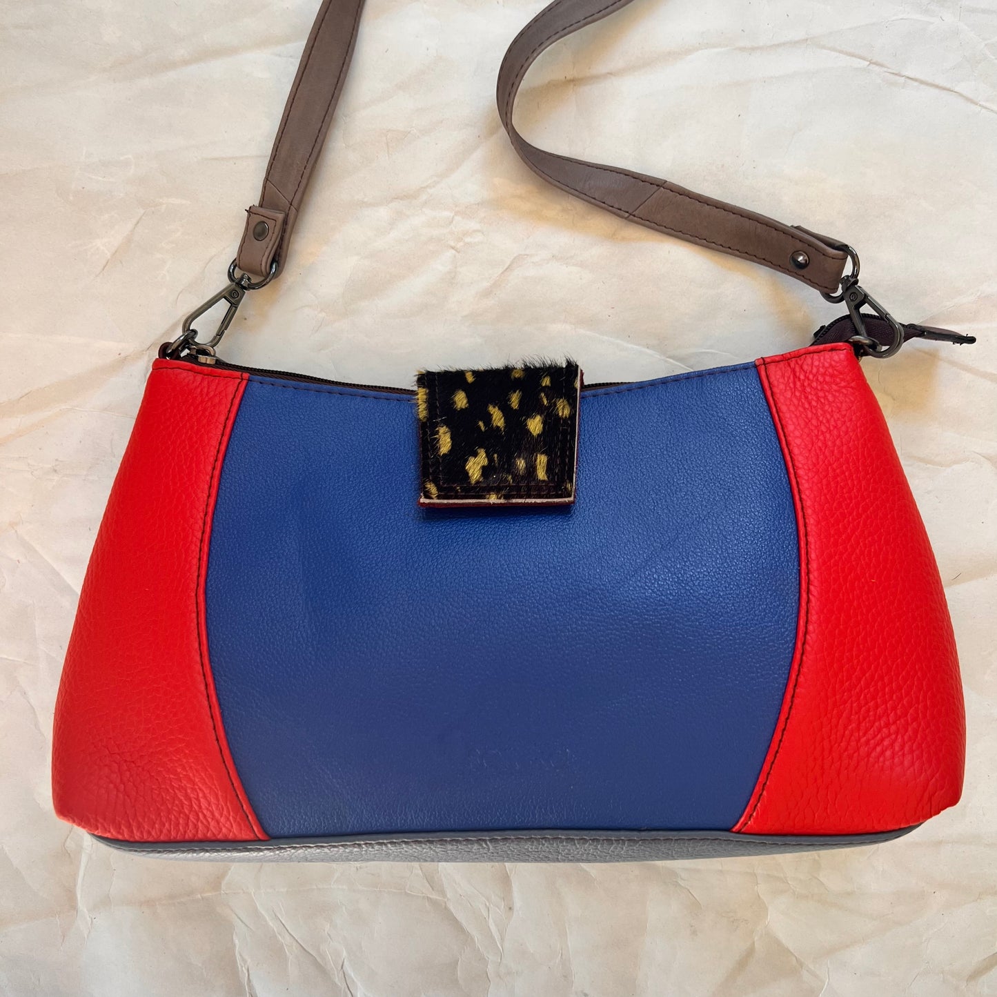 front on Amanda bag with color blocks of red and blue and an animal print tab over top zipper.