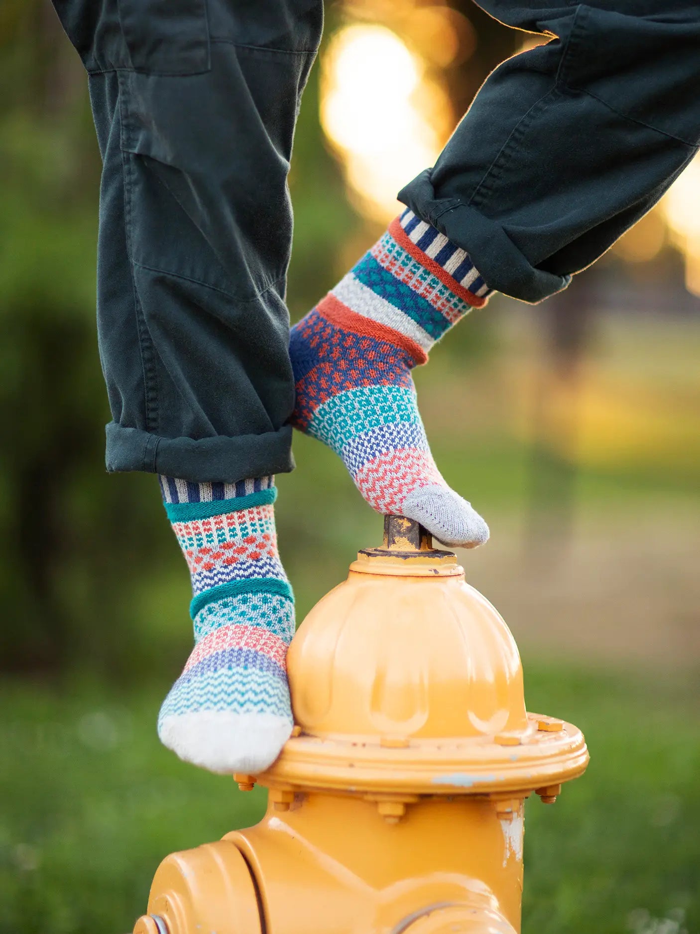 person wearing blue pants and Mirabell Crew Socks standing on a yellow fire hydrant