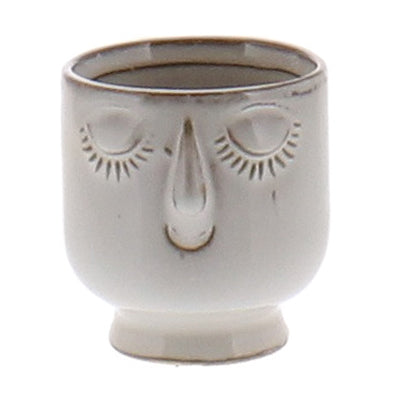 white ceramic pot with a smiling face and closed eyes