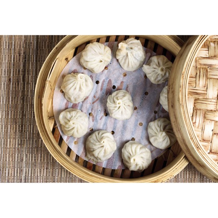 Steamed buns in a bamboo steamer on a woven mat