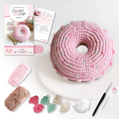 Crocheted pink donut with yarn, hooks, and instructions on a white background
