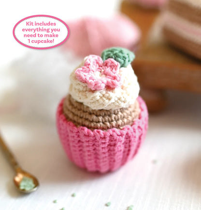 Crocheted cupcake with pink frosting and green leaves on a white background