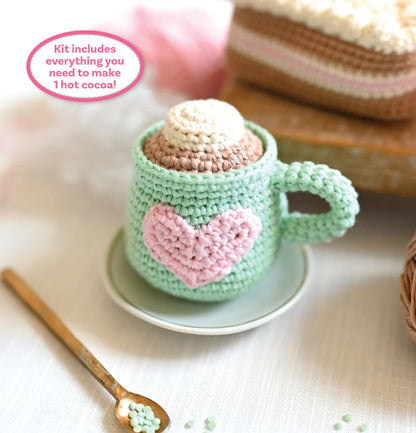 Crocheted green mug with pink heart and marshmallow on a white surface