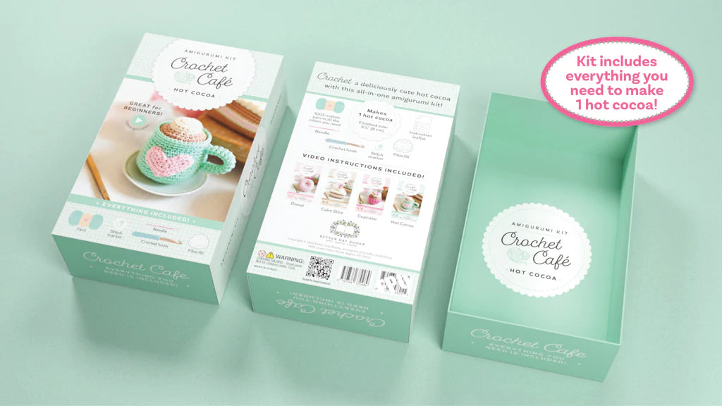 Three mint green boxes for a 'Crochet Café Hot Cocoa' kit arranged on a matching mint green background, with a pink circular callout in the top right stating 'Kit includes everything you need to make 1 hot cocoa!'.