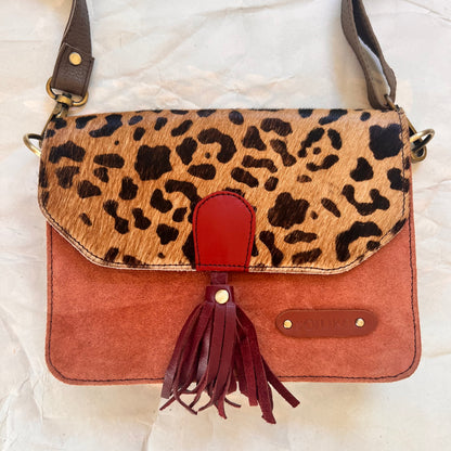 front of Claire purse with an coral body, cheetah print flap, and maroon tassel.