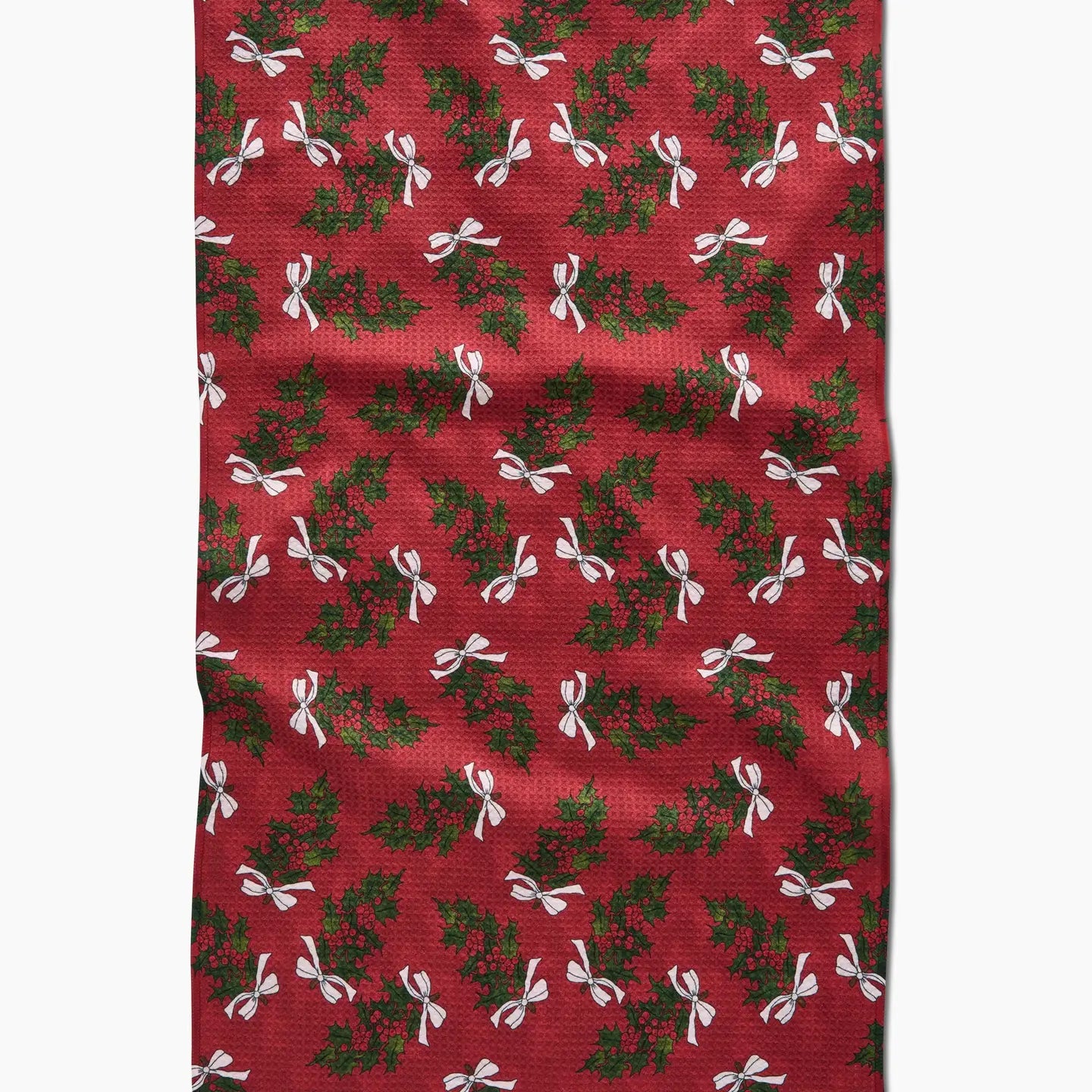 red towel printed with green holly sprigs tied with a white bow