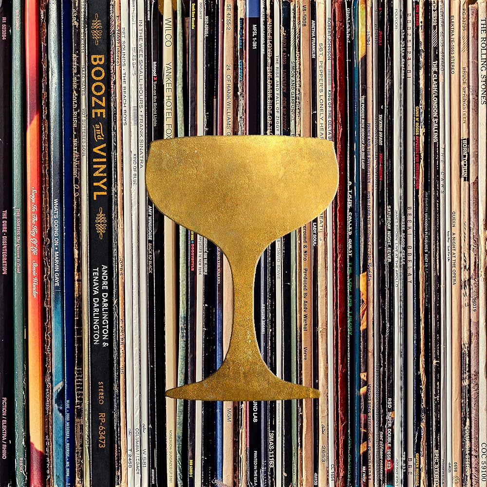 close-up of front cover of Booze & Vinyl with image of the spines of many vinyl sleeves and golden bar glass