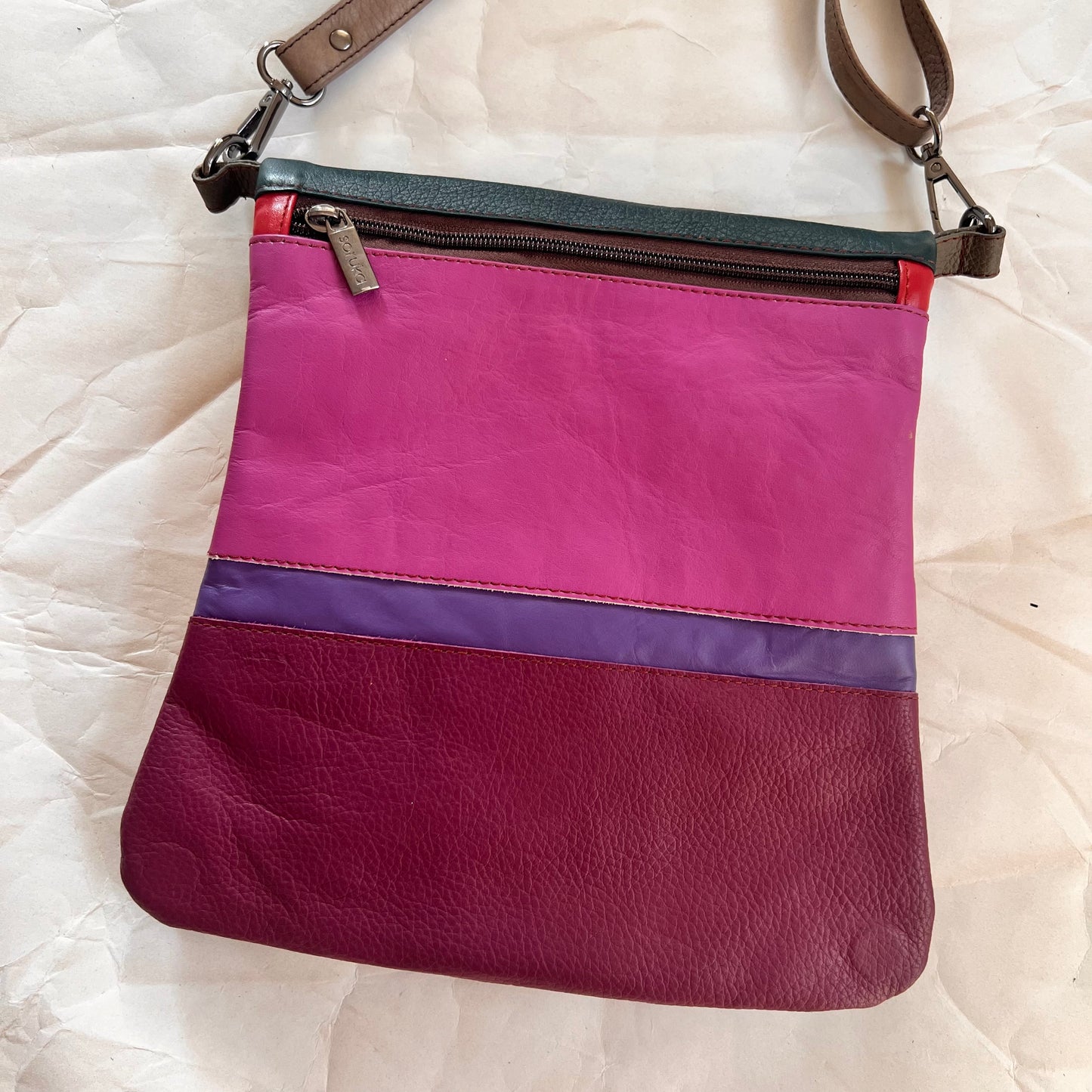 pink, purple and plum striped greta bag with zipper across the top.