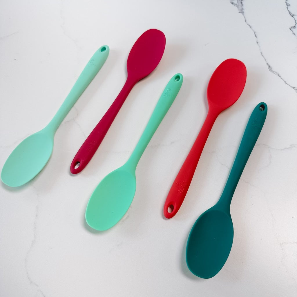 5 colors of mini spoons arranged at and angel on a marble background.