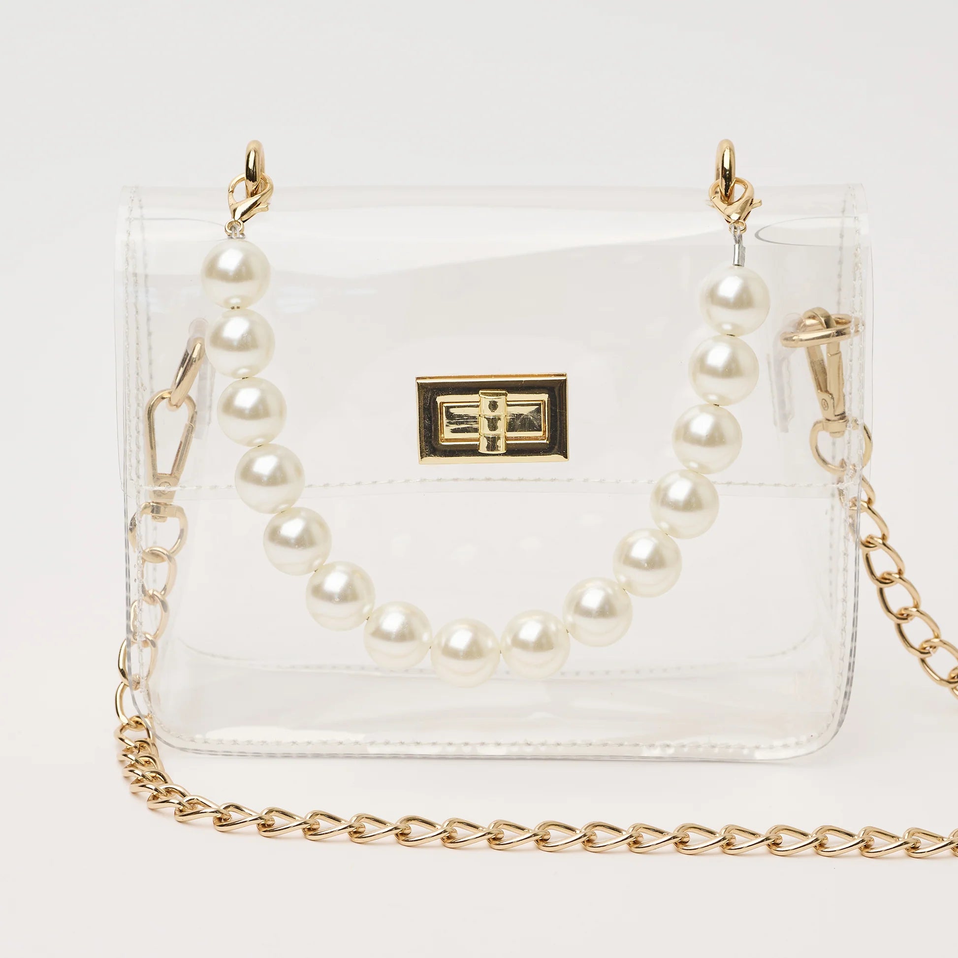 clear handbag with short pearl handle and longer gold chain crossbody strap. The bag has gold hardware and a square shape.