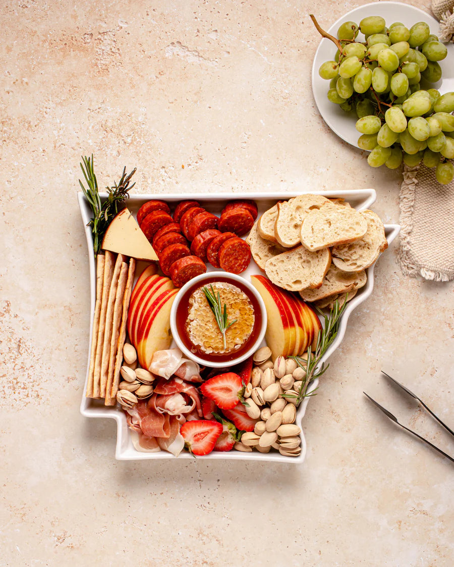 white, Arkansas shaped dish filled with snacks and dip,