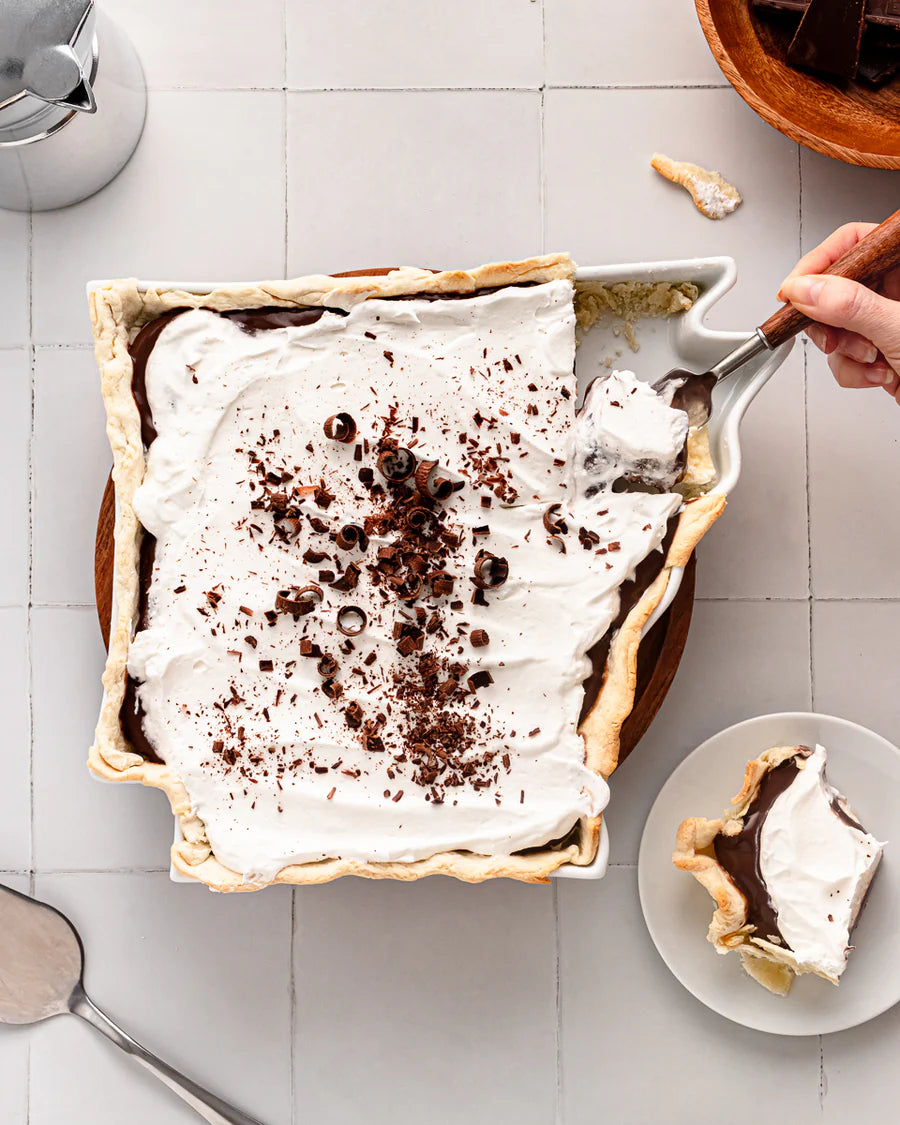 white Arkansas shaped dish filled with a chocolate dessert topping with whipped cream.