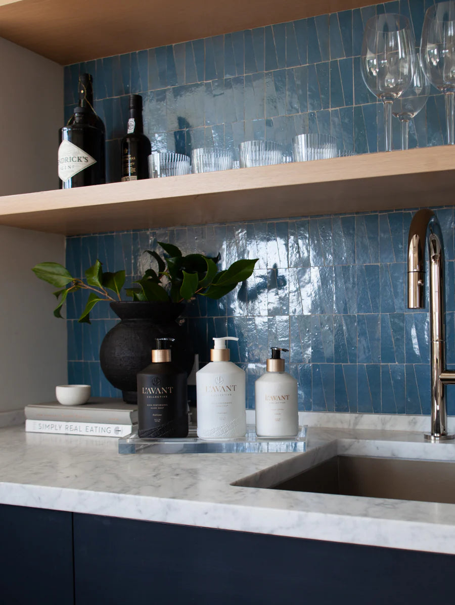 large acrylic tray with three  bottles on it next to a sink