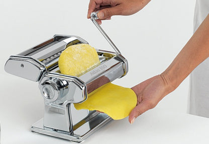 hands rolling pasta dough out of the Atlas Classic Pasta Machine