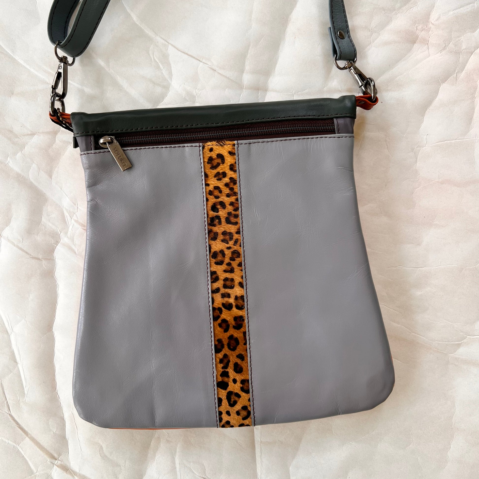grey greta bag with animal print stripe down the center and zipper at the top.