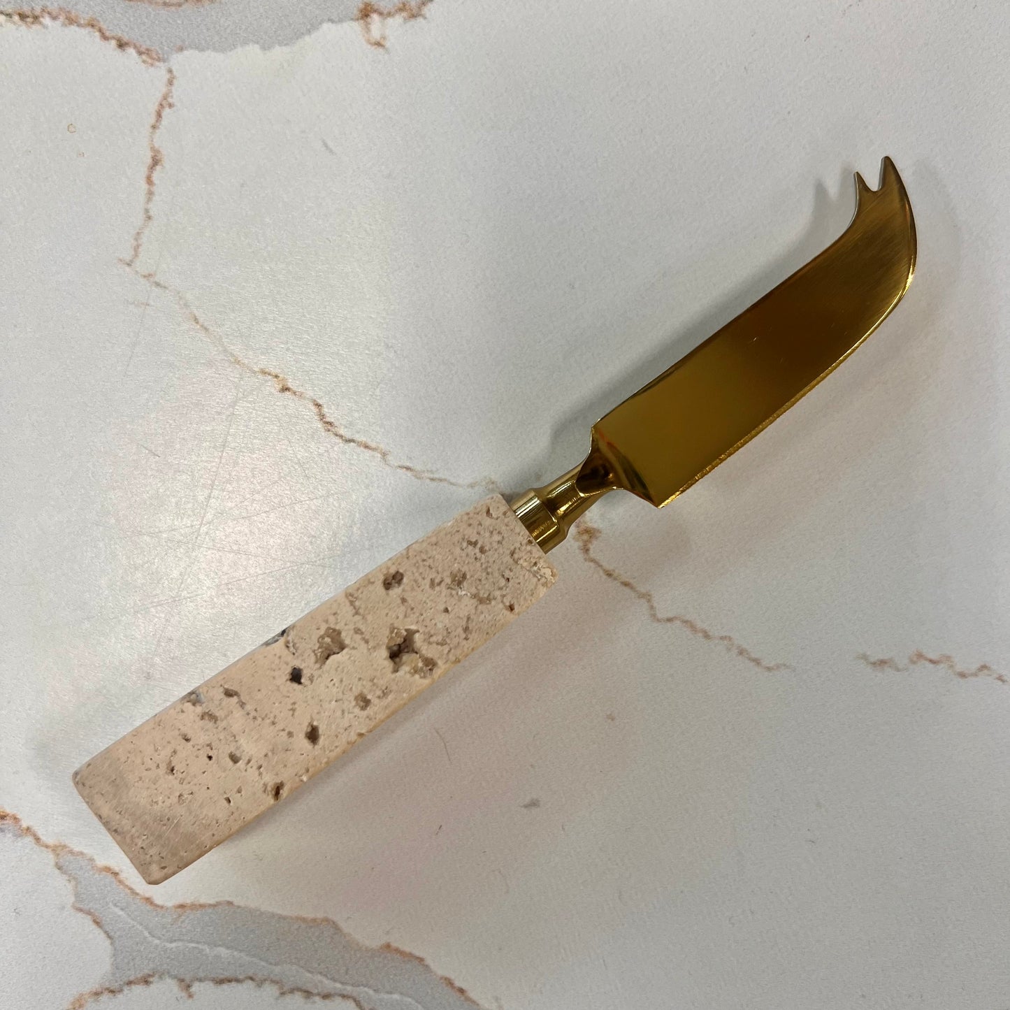 white travertine handled pronged cheese knife.