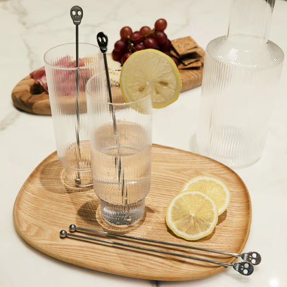 beverages on a wood board with skull cocktail stirrers in them.