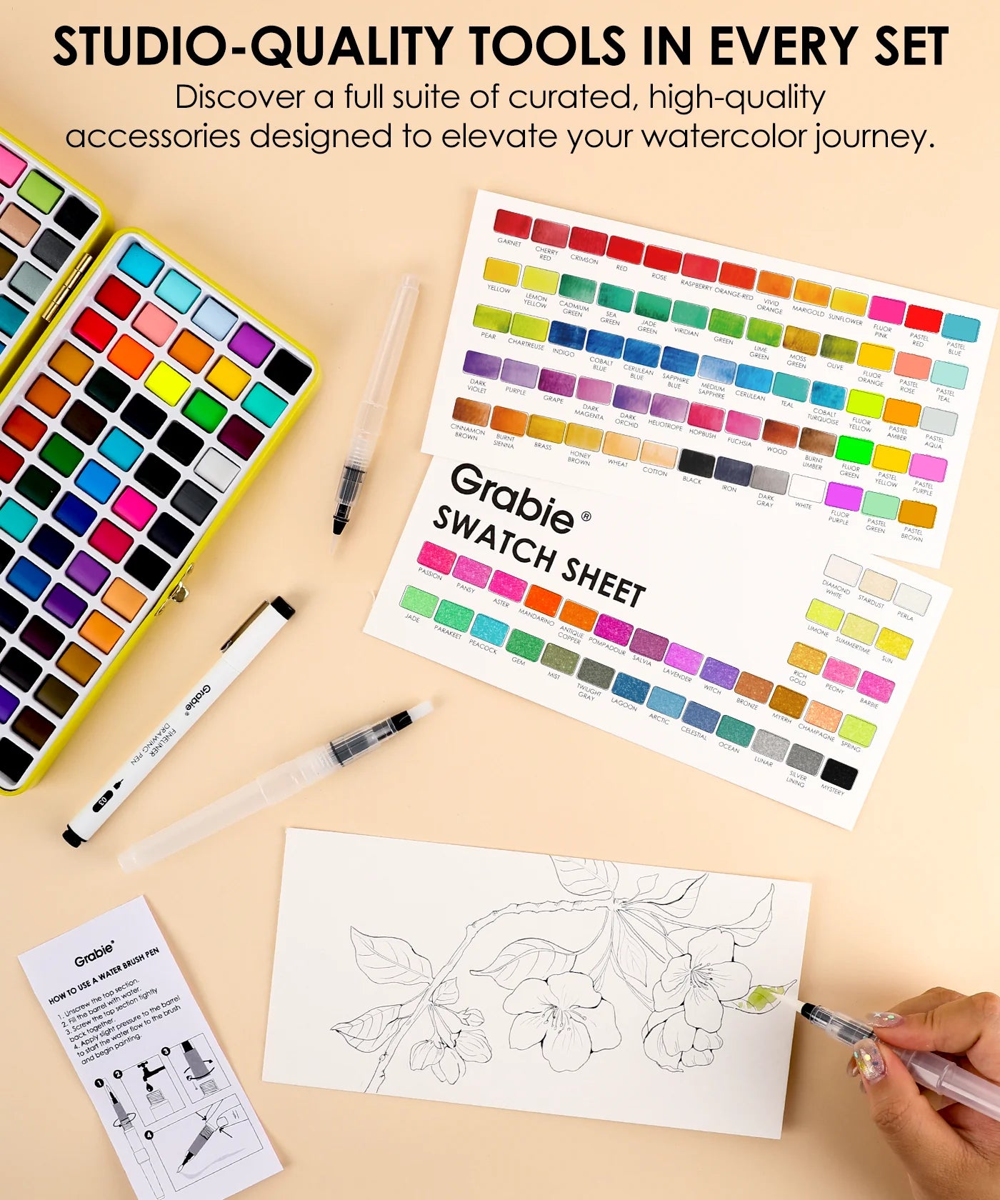 Set of watercolor tools including a color chart, swatch sheet, and coloring book on a beige surface.