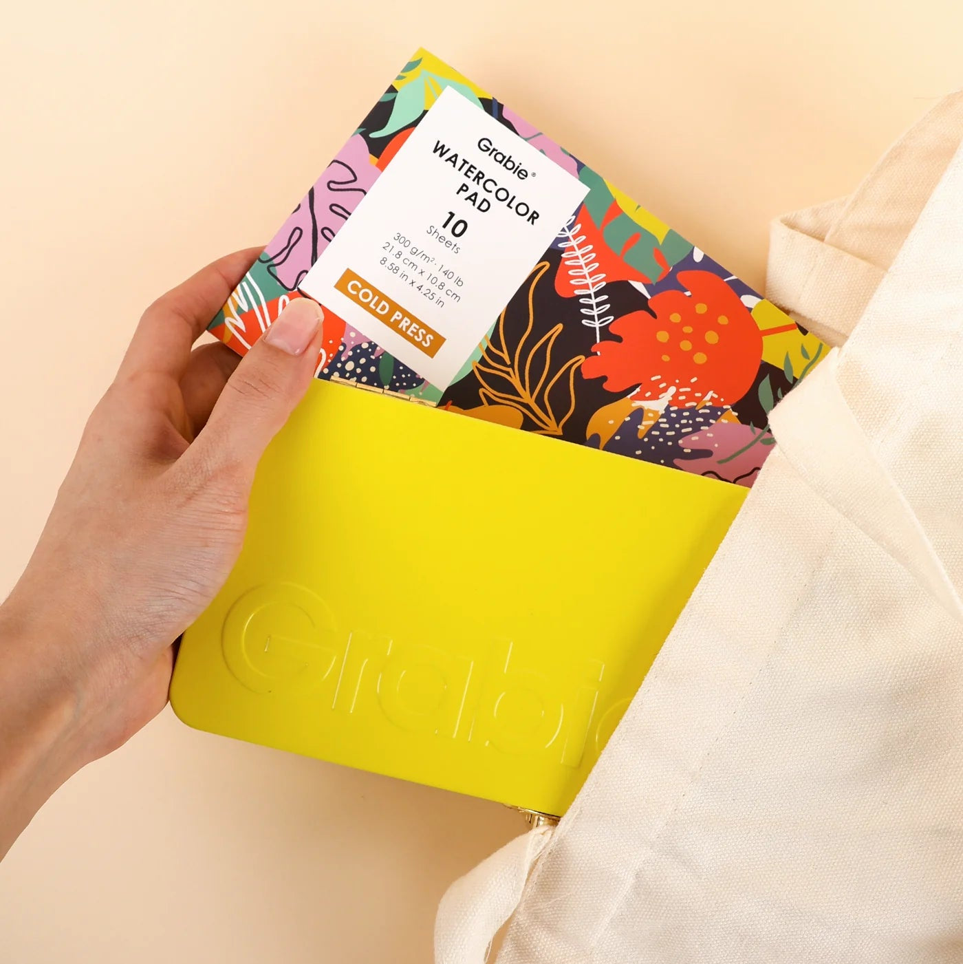 hand holding grabie essential watercolor kit and watercolor pad