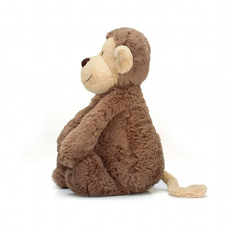 side view of the small bashful monkey plush toy on a white background