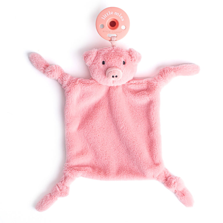 pink pig lovely with pacifier attached laying flat on a white background.