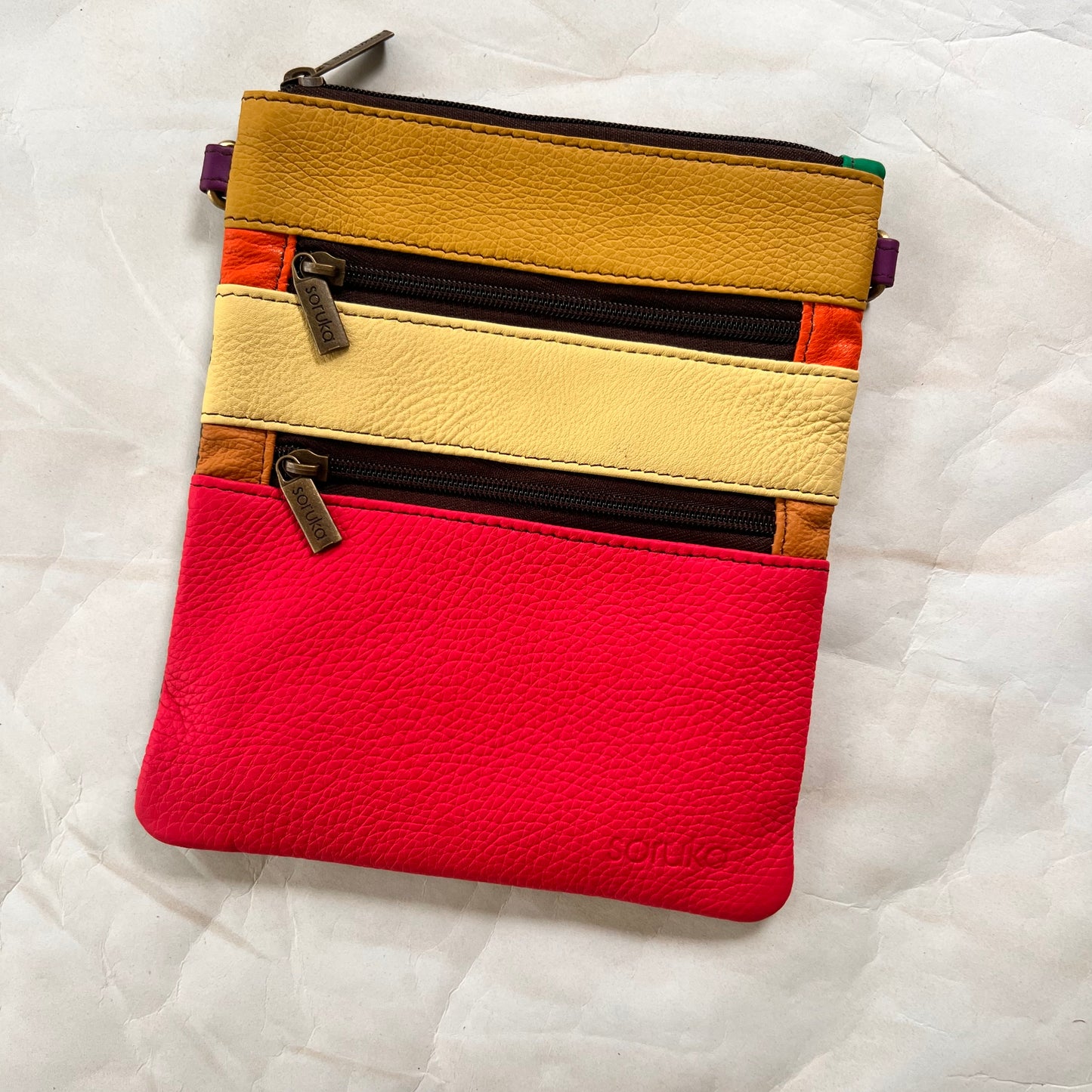 flat rectangular maya bag with top zipper and 2 zipper pockets color blocked in pink and yellows.