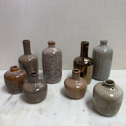 all 8 styles of small stoneware vases grounded on a table.