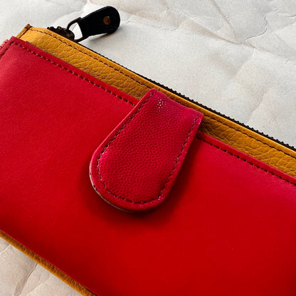 close-up of rectanglar kimber mustard wallet with raspberry colored pocket and pink tab closure.