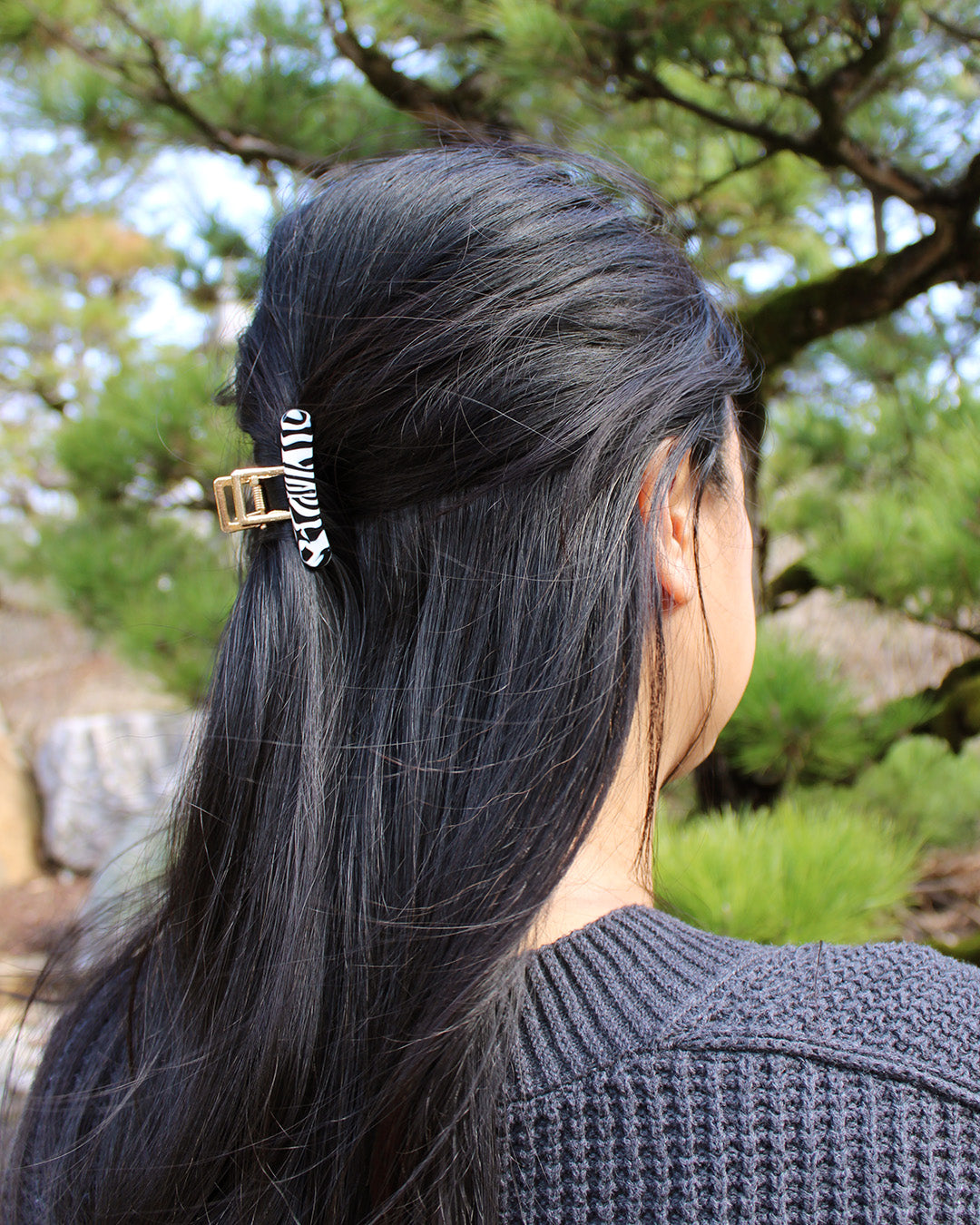 person with long black hair clipped with a black and white claw clip.