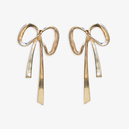 golden metal bow shaped earrings on a white background.