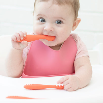 baby sitting in highchair chewong of silicone utensils.