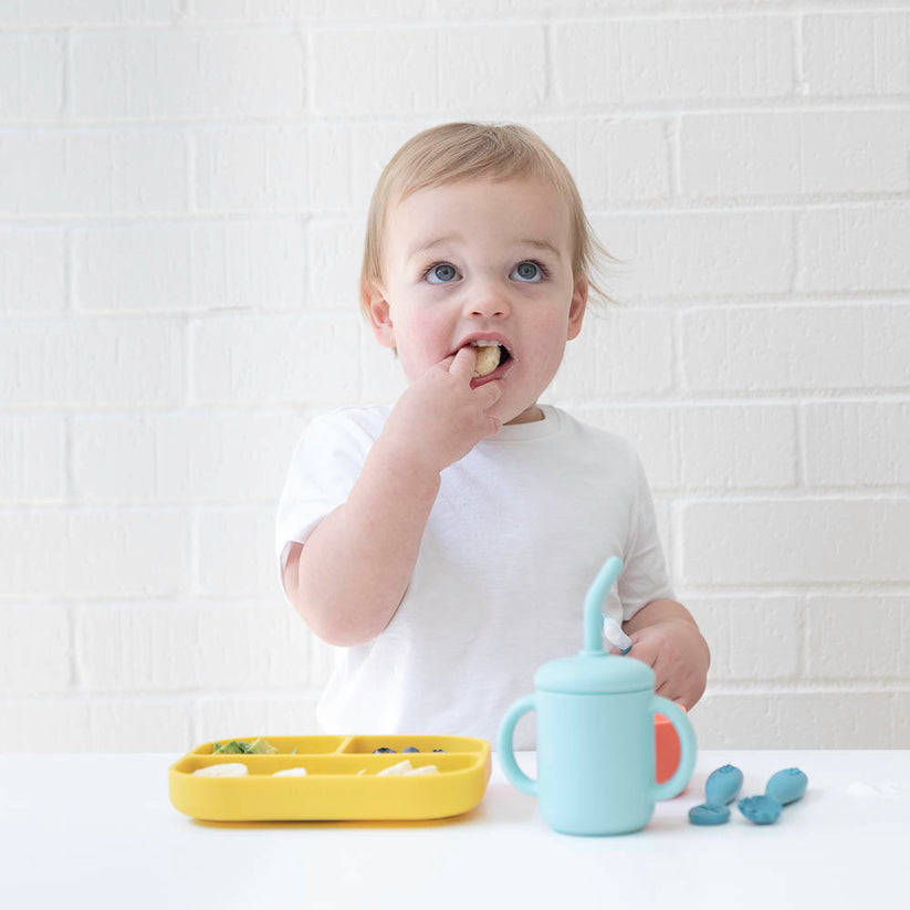 toddler feeding themself from silicone dishes.