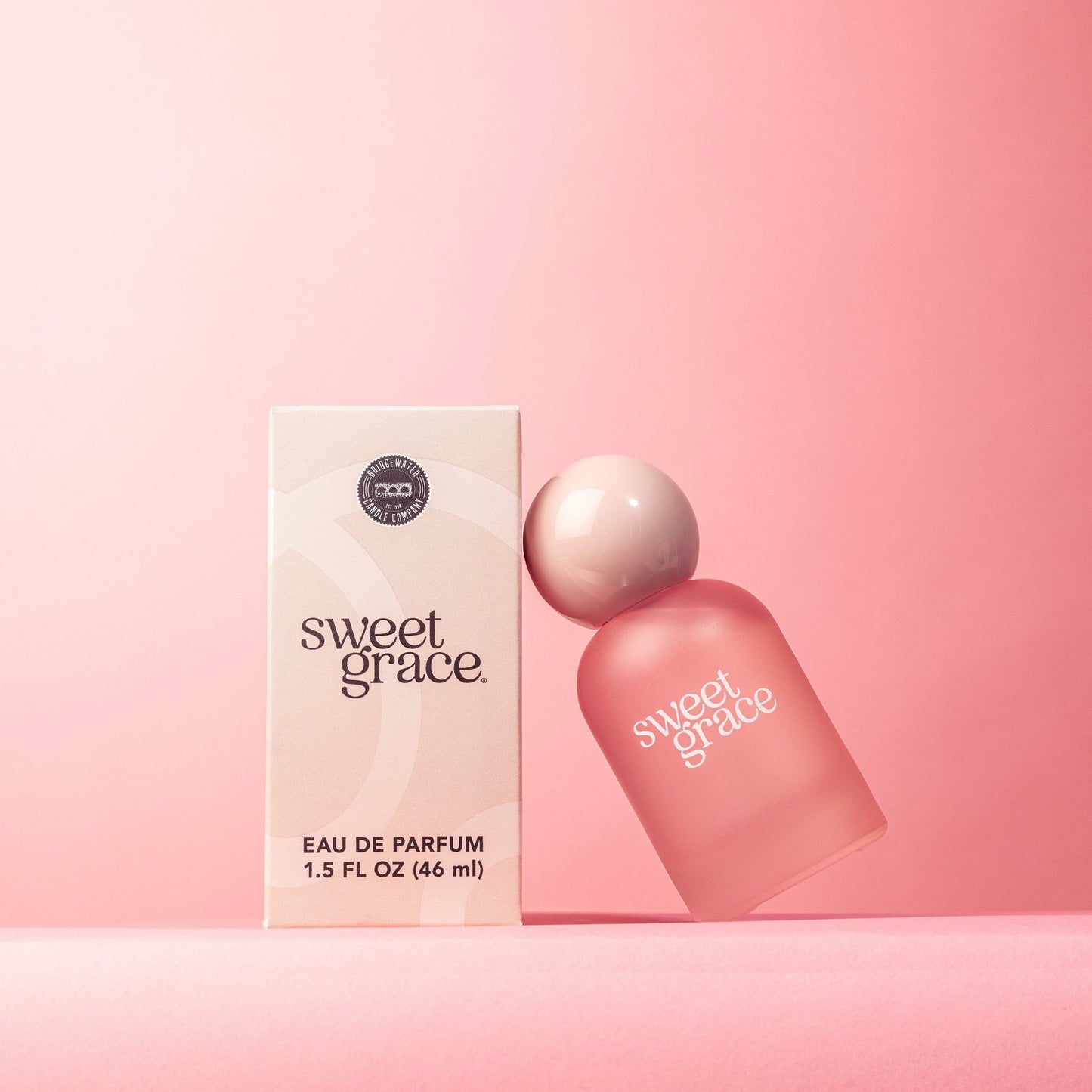 sweet grace parfum bottle leaning on its box packaging shown on a pink background