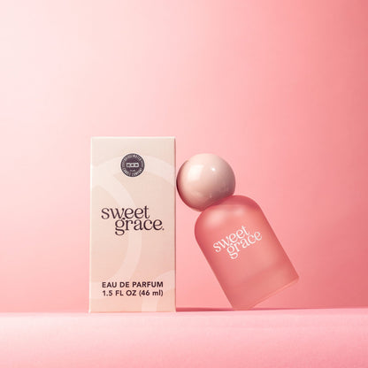 sweet grace parfum bottle leaning on its box packaging shown on a pink background